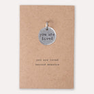 you are loved charm on card with writing you are loved beyond measure