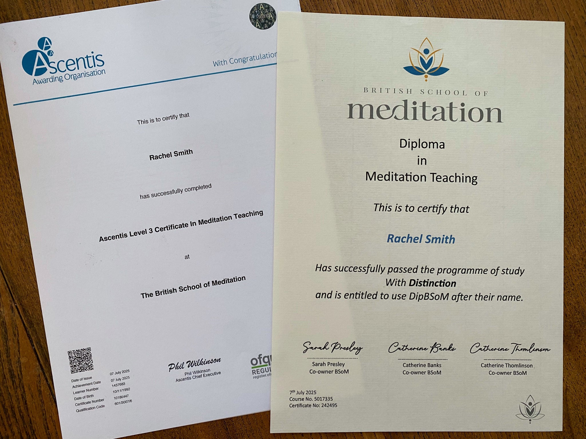 Two certificates from Ascentis and The British School of Meditation on a wooden surface.